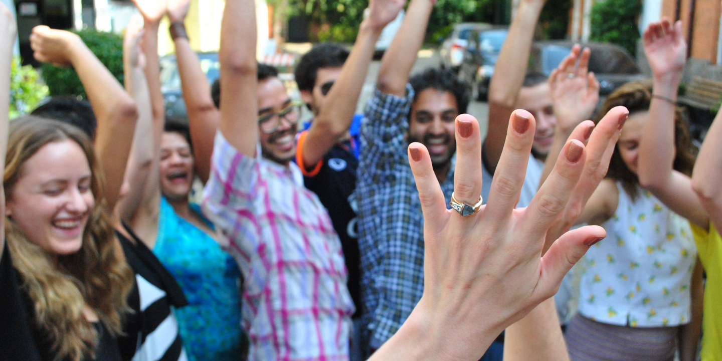 Group of people laughing with their hands up